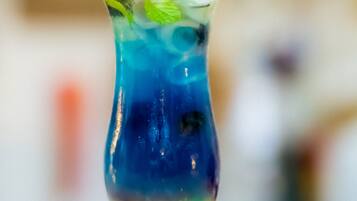 A tall glass with layered drinks and a colorful umbrella on top.
