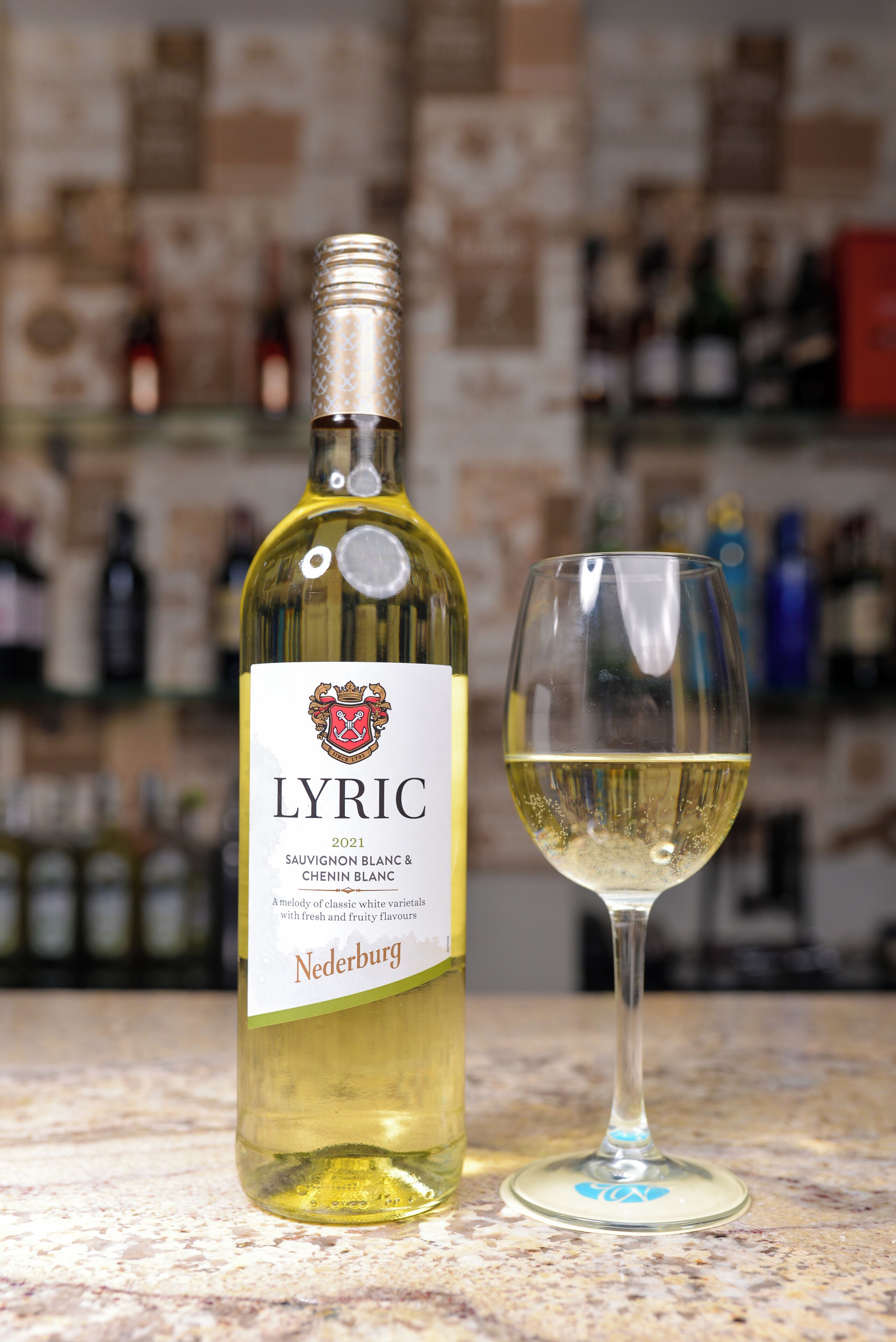 A bottle of 2021 Lyric Sauvignon Blanc & Chenin Blanc wine with a glass of white wine beside it.