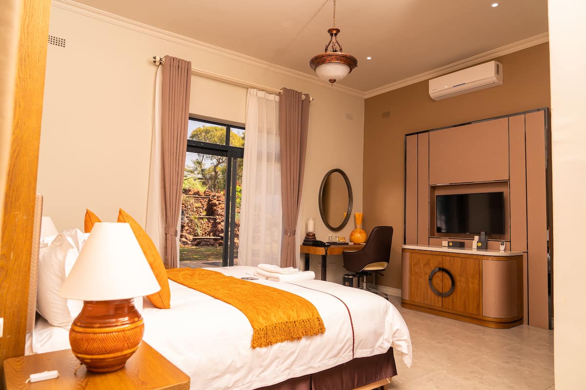 Een hotelkamer met een bed, een bureau, een stoel, een televisie en een airconditioner.