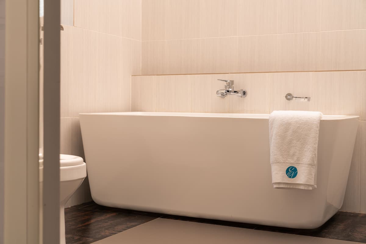 Een moderne badkamer met een vrijstaand bad, een toilet en een handdoek aan het bad.