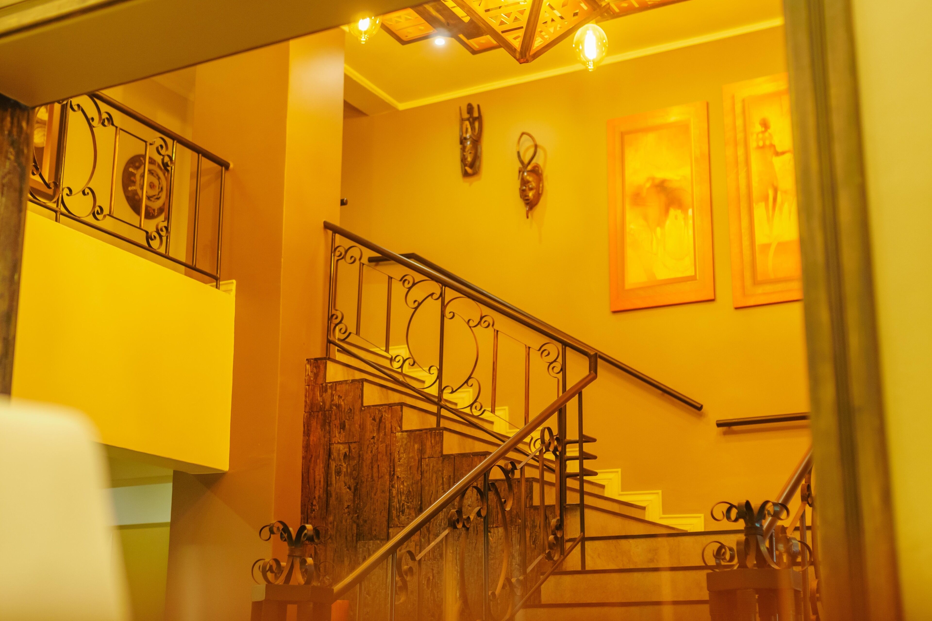 A staircase with ornate metal railings and wooden steps, leading to an upper floor.