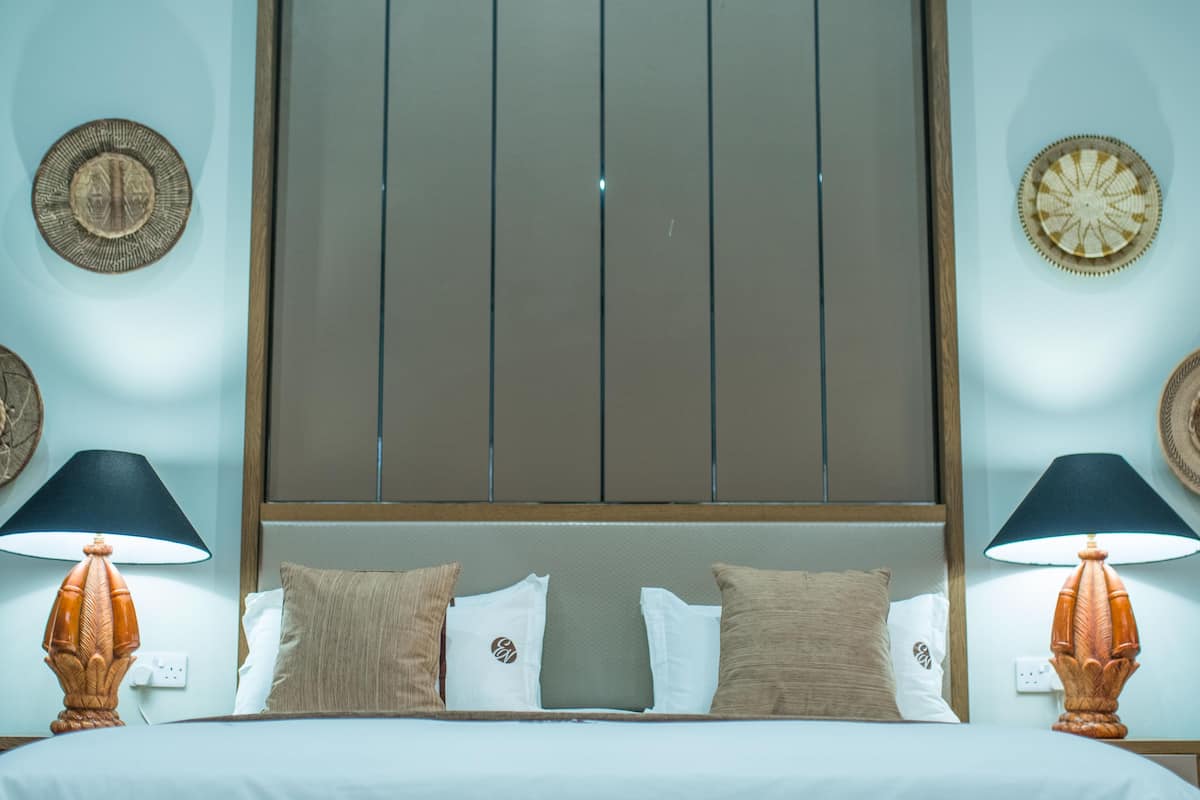 Een hotelkamer met een bed, twee bedlampen en decoratieve wandplaten.