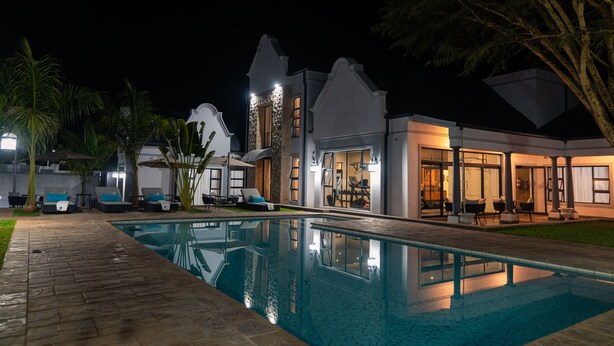A modern house with a swimming pool, outdoor seating, and a well-lit patio area.