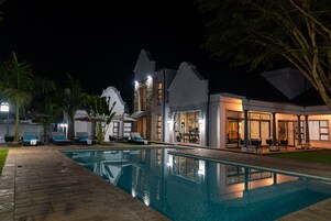 Una piscina al aire libre, sombrillas, sillones reclinables de piscina