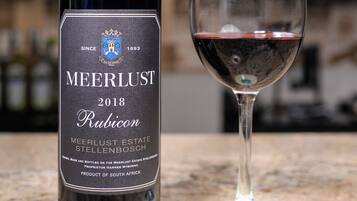 Una botella de vino Meerlust Rubicon y una copa de vino tinto sobre una encimera de mármol.