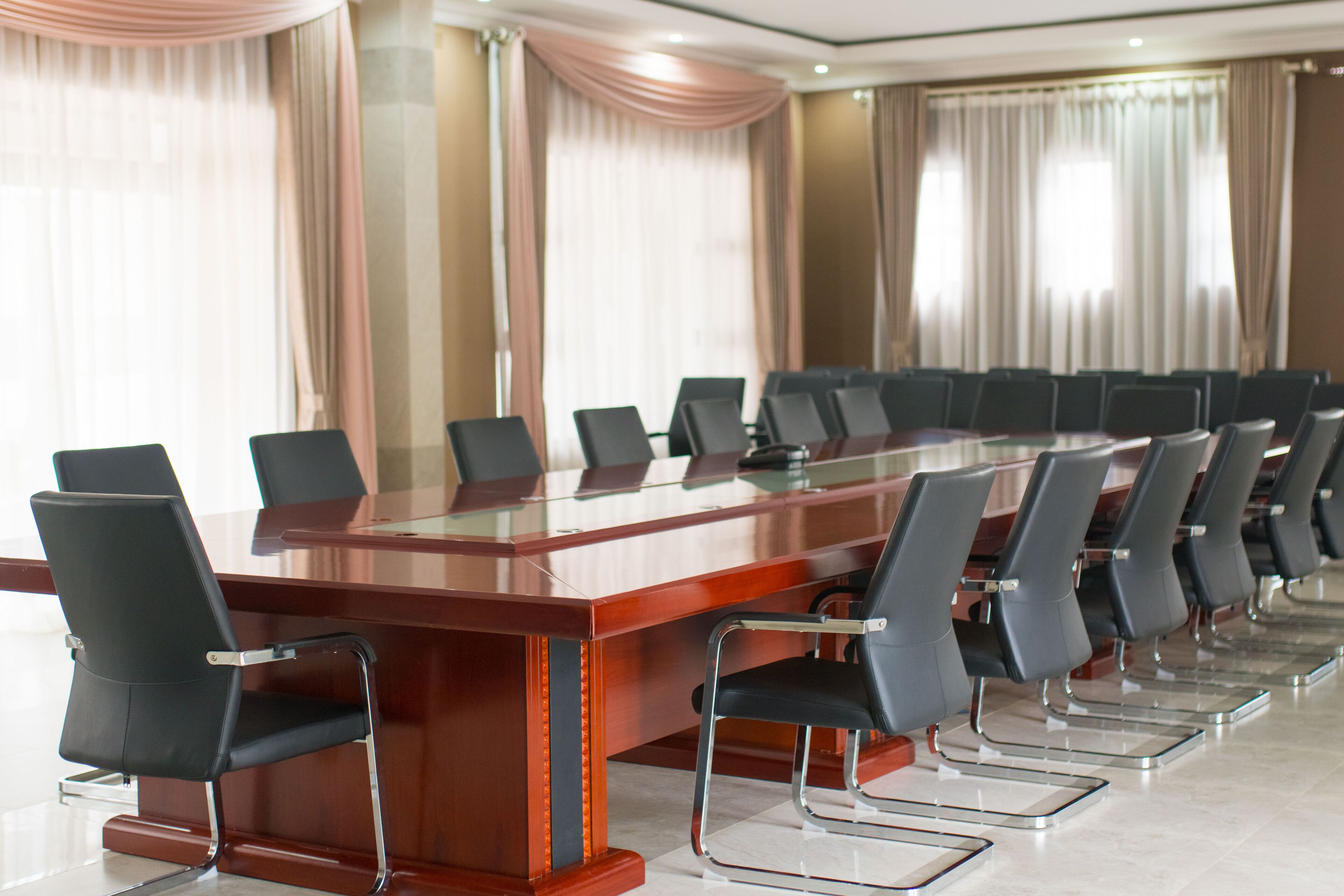 A conference room with a long table and chairs, large windows with curtains, and a modern interior design.