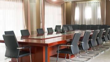 A conference room with a long table and chairs, large windows with curtains, and a modern interior design.