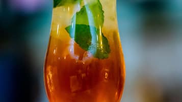 A cocktail glass with a clear liquid, ice cubes, and mint leaves.