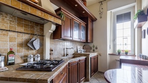 A kitchen with a gas stove, wooden cabinets, a tiled backsplash, and a window with a view. - [St. Peter's view point] Elegant apartment (Roma)