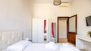 A hotel room with a bed, a wardrobe, a mirror, and a TV on the wall. - [St. Peter's view point] Elegant apartment (Roma)