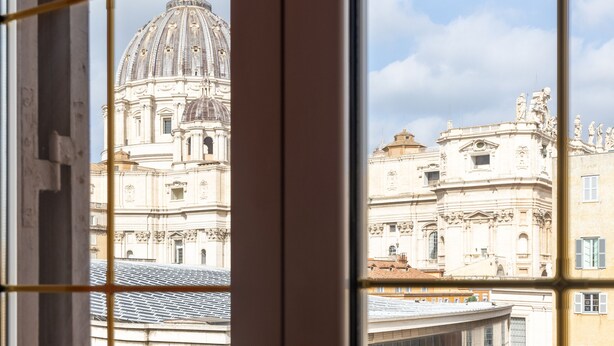 A view through a window with a grid pattern, featuring a large dome and classical architecture. - [St. Peter's view point] Elegant apartment (Roma)