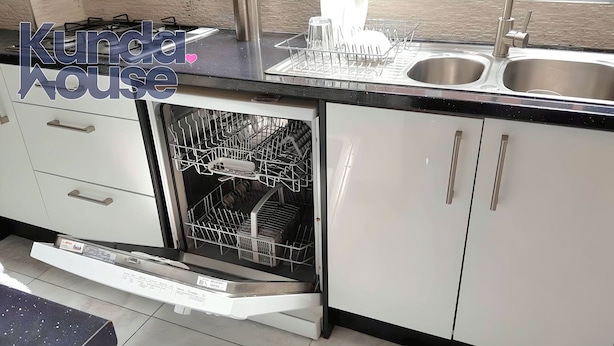 A kitchen with a Bosch dishwasher, stainless steel sink, and white cabinets. - Kunda House Bournbrook (Birmingham)