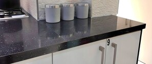 A kitchen counter with three stainless steel containers labeled "sugar," "coffee," and "tea." - Kunda House Bournbrook (Birmingham)