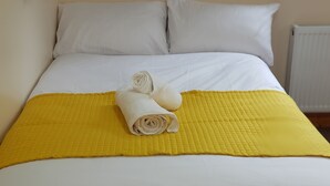 A neatly made bed with white linens and a yellow quilted bedspread. - Kunda House Bournbrook (Birmingham)