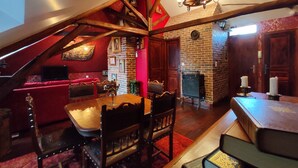 A cozy attic room with a dining table, chairs, a red sofa, and a fireplace.