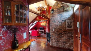 A cozy room with a brick wall, wooden beams, and a red sofa.