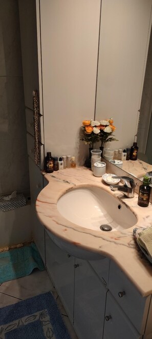 Een bad/douchecombinatie, een haardroger, handdoeken, zeep