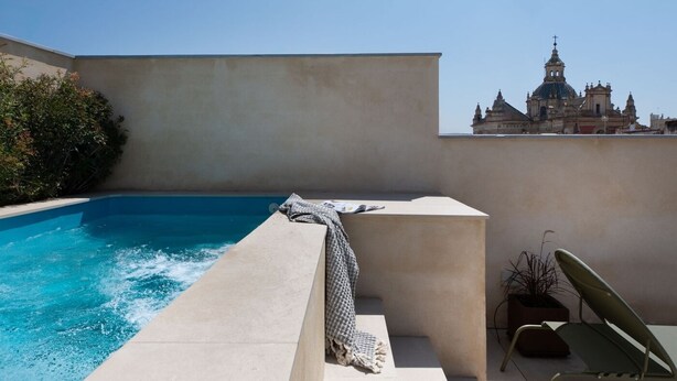 Una piscina en la azotea con vistas a un edificio histórico al fondo.
