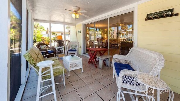 A covered patio area with wicker furniture, a ceiling fan, and a sign that reads "Relaxing the Porch". - Perfect Island Location! Heated pool and plenty of room for the entire family (Anna Maria)