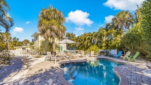 A swimming pool with a brick border, surrounded by lounge chairs and a palm tree. - Perfect Island Location! Heated pool and plenty of room for the entire family (Anna Maria)