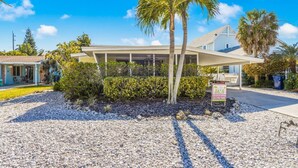 A hotel with a covered outdoor seating area, palm trees, and a signboard. - Perfect Island Location! Heated pool and plenty of room for the entire family (Anna Maria)