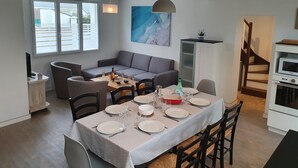 A modern kitchen and dining area with a dining table set for four, a sofa, and a cabinet. - Comfortable house 700m from the beach and 800m from the shops (Pénestin)