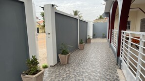 A narrow, tiled corridor with potted plants and a gated area. - Captivating 5-bedroom Duplex With 4 Toilets (Brufut)
