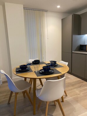 Un espace repas moderne avec une table ronde en bois, des chaises blanches et de la vaisselle bleue.