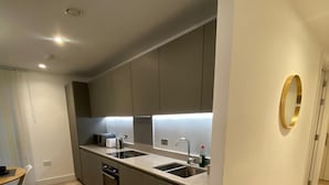 Ett modernt kök med en central köksö, inbyggda vitvaror och en stilren design.