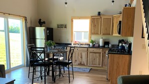 Une cuisine spacieuse avec des meubles en bois, un coin repas comprenant une table et des chaises, et une grande fenêtre laissant entrer la lumière naturelle.