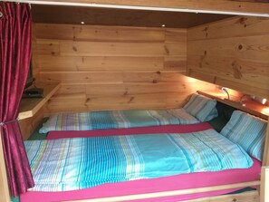 A wooden cabin room with a bed, a small table, and a red curtain. - Boat with a view in center of Amsterdam (Amsterdam)