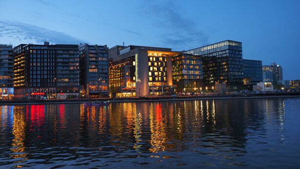 Ein moderner Gebäudekomplex mit mehreren Stockwerken, großen Fenstern und Blick auf das Wasser.