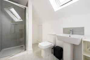 A modern bathroom with a glass-enclosed shower, a white toilet, and a sink with a grey backsplash. - Modern Apartment, Castle View Rochester, England (Rochester)
