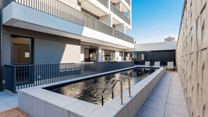 A modern building with a swimming pool, outdoor seating, and a fitness center.