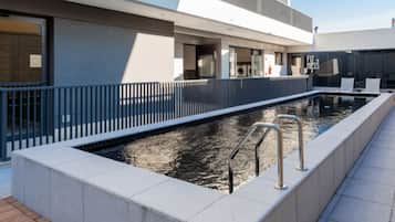 Una piscina al aire libre, sillones reclinables de piscina