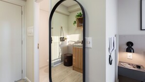 A modern bathroom with a wooden vanity, a mirror, and a small shelf with a plant.