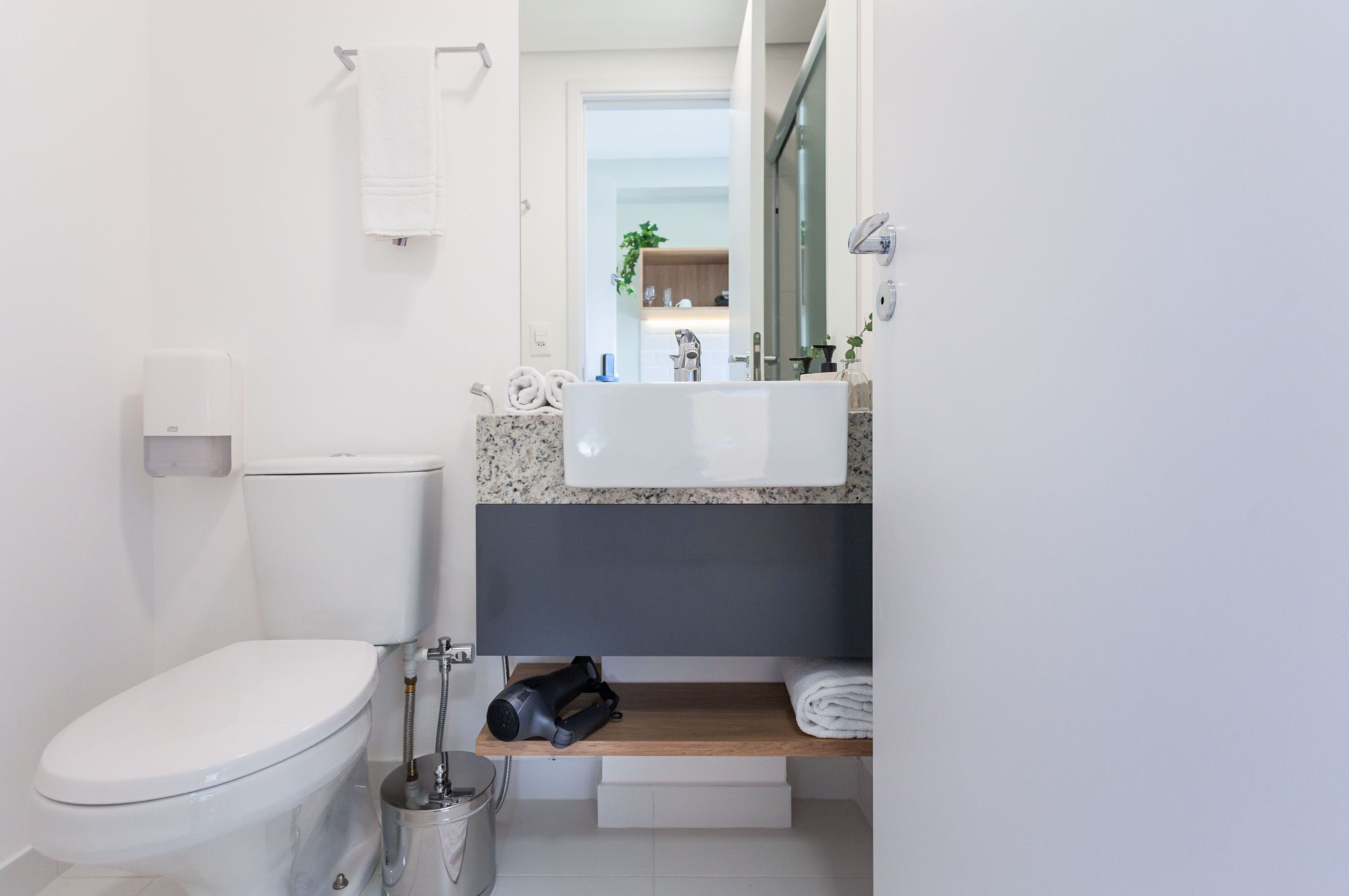 A modern bathroom with a toilet, sink, and towel rack.