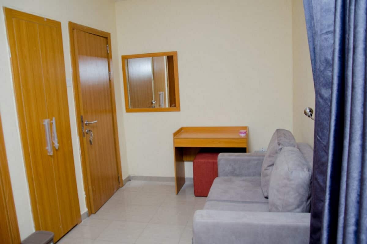 A room with a grey sofa, a wooden desk, and two wooden doors.