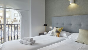 A modern hotel room with a large bed, a nightstand, a lamp, and a view of the outside balcony.
