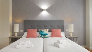 A double bed with two pillows, a headboard, and two bedside lamps.
