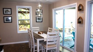 Un comedor con una mesa, sillas y vistas a un patio exterior a través de un ventanal.