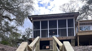 Una escalera de madera que conduce a un edificio con ventanas amplias y un espacio cubierto en la parte superior.