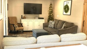 Una sala de estar con un sofá, un televisor, un árbol de Navidad y un ventilador de techo.