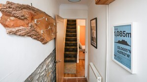 A hallway with a rustic wall, a staircase, and a framed map on the wall. - 5 Thomas Street (Caernarfon)