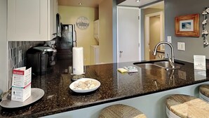 Une cuisine moderne dotée d’un plan de travail en granit, d’appareils électroménagers en acier inoxydable et d’une grande fenêtre.