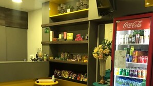 Un petit comerç de proximitat amb estanteries plenes d'aperitius, un refrigerador de Coca-Cola i una taula petita amb un cendrer.