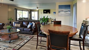 Un vaste espace de vie comprenant une table à manger en bois, un canapé en cuir et une table basse en verre.