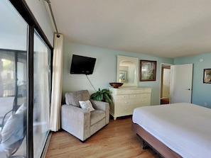A bedroom with a bed, a dresser, a television, and a window. - Edgewater Villa #2209 | Lake View, Beach Tram + Resort Amenities (Panama City Beach)