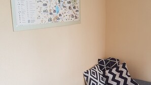 A small, single-bed room with a patterned bedspread and pillows, a map on the wall, and a plain wall. - Idyllic vacation apartment on the farm  (Baruth)