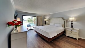 Un dormitorio con una cama grande, mesitas de noche, un aparador y vistas a un balcón.